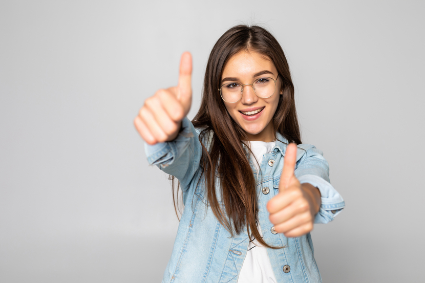 menina feliz fazendo sinal positivo com as duas mãos