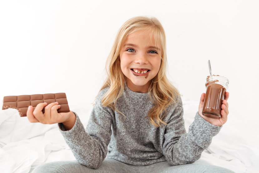 menina lambuzada de chocolate com chocolate nas duas mãos
