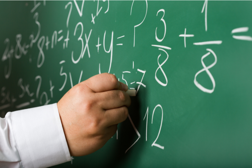 mão de criança escrevendo contas de matemática na lousa