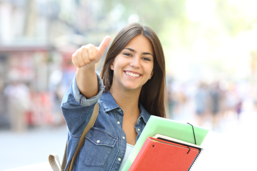 melhor escola de Rio Branco estudante fazendo sinal de positivo com material escolar na mão