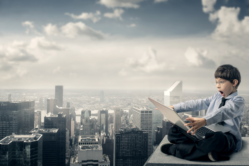 criança vestida como profissional em cima de um prédio olhando assustada para um computador