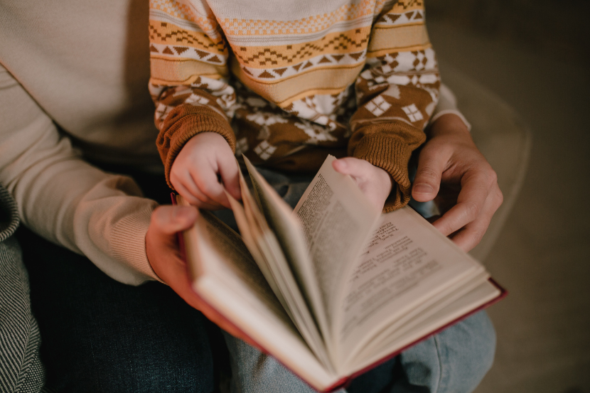 filho folheando um livro no colo do pai