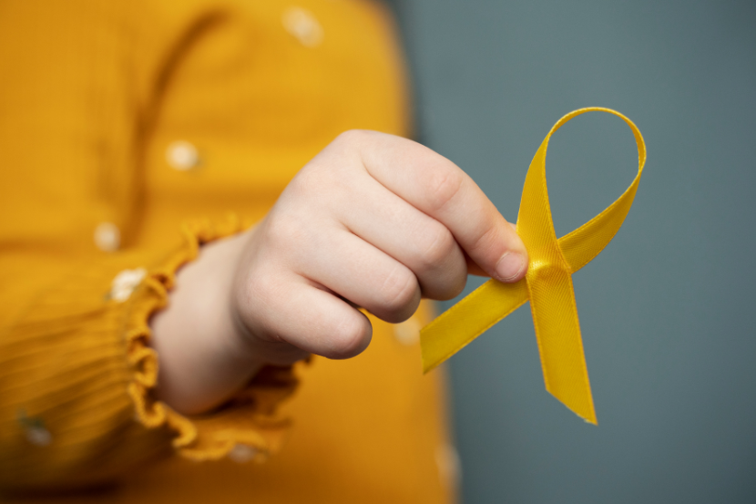 criança segurando fita amarela do setembro amarelo na mão 