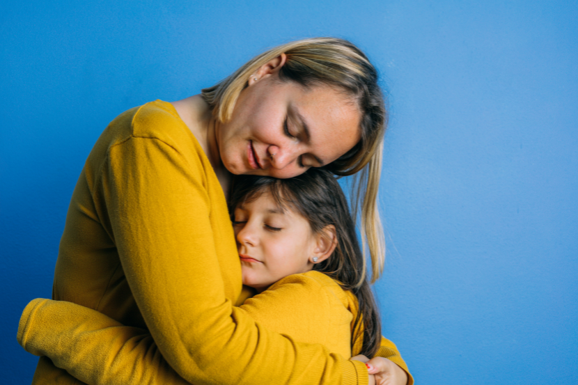 mãe abraçando filha em sinal de acolhimento, as duas estão com roupas amarelas
