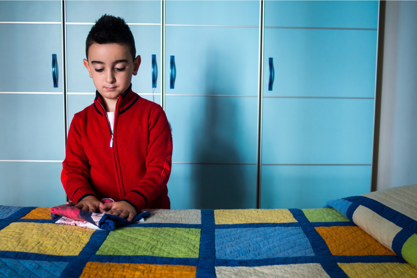 criança dobrando a roupa em cima da cama