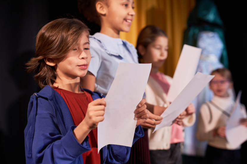 crianças lendo roteiro de teatro em ensaio