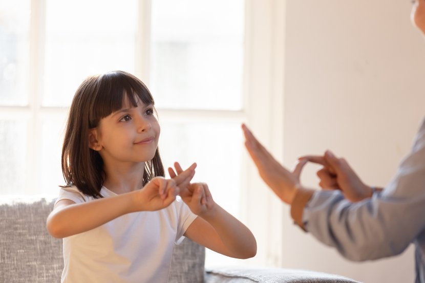 criança praticando libras em casa com a mãe