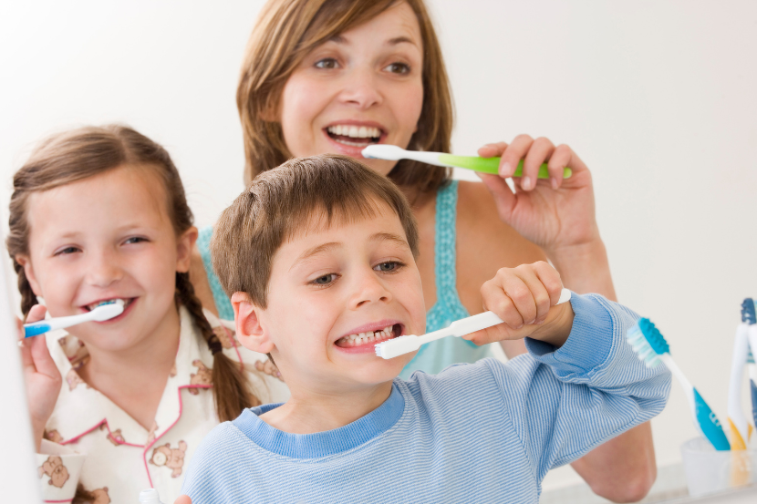 mãe escovando os dentes com os filhos