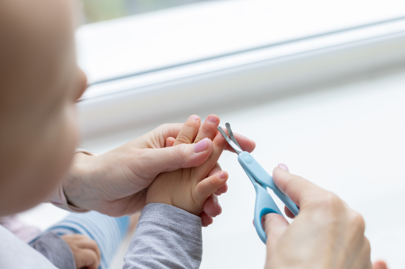 mãe cortando a unha do bebê