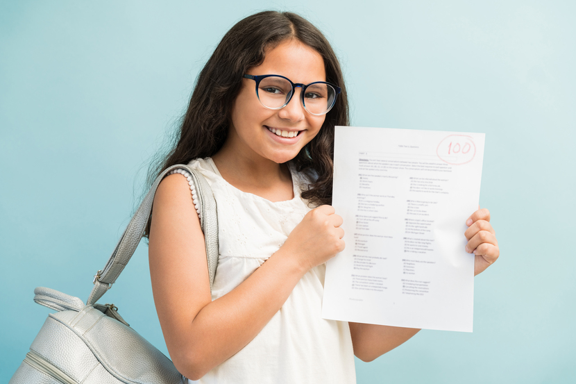 menina feliz segurando boletim escolar com nota 100