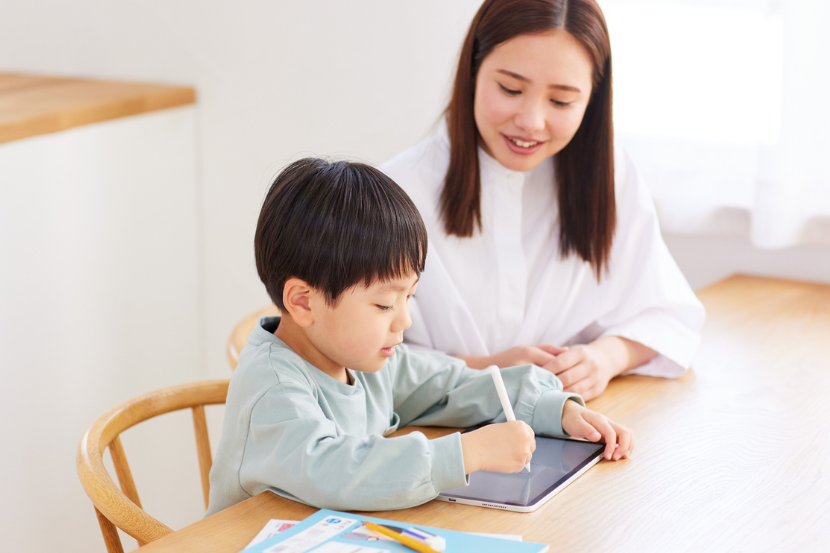 mãe ensinando filho a escrever no tablet