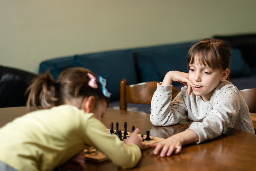 duas meninas jogando xadrez em casa