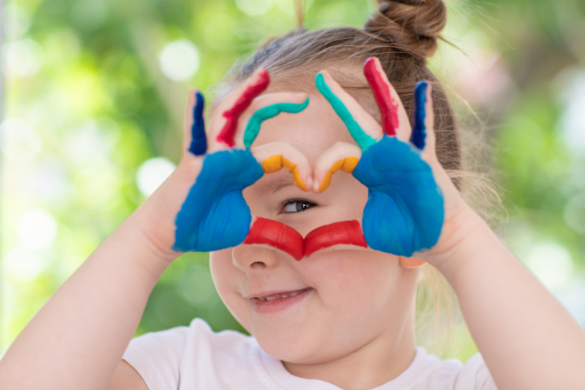 criança com as mãos pintadas de tinta fazendo coração