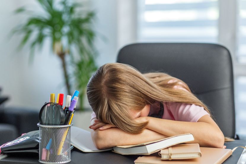 criança cansada dormindo em cima dos livros