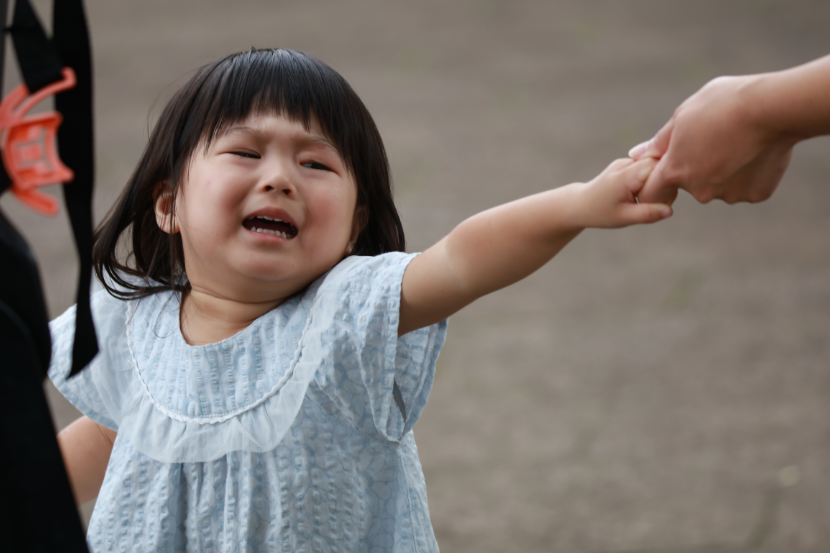 menina chorando segurando mão da mãe