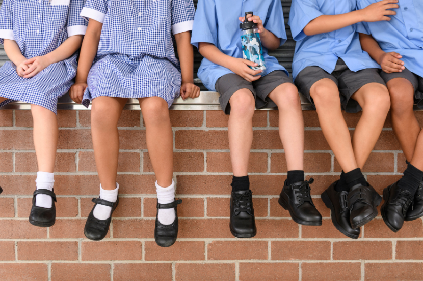 crianças sentadas com uniforme escolar