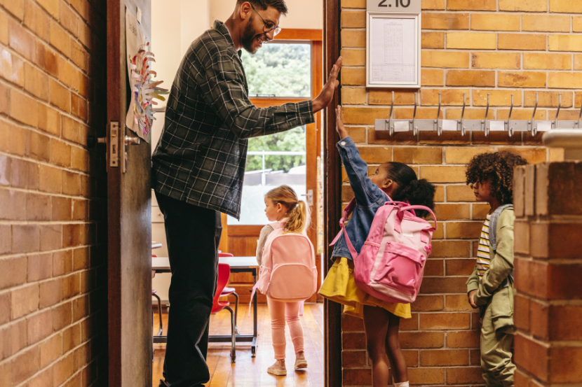 pós-volta às aulas professor recebendo alunos na porta da sala de aula