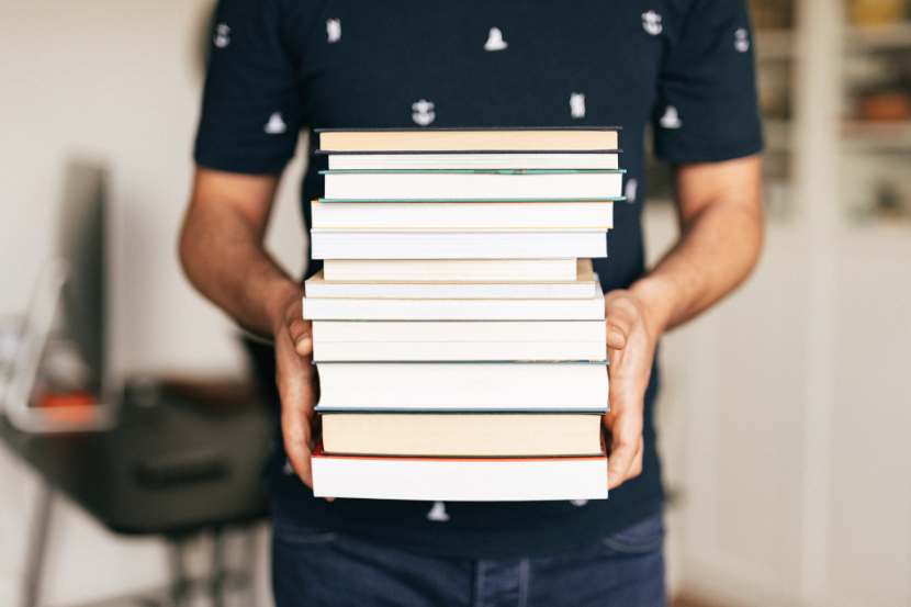 aluno segurando livros empilhados