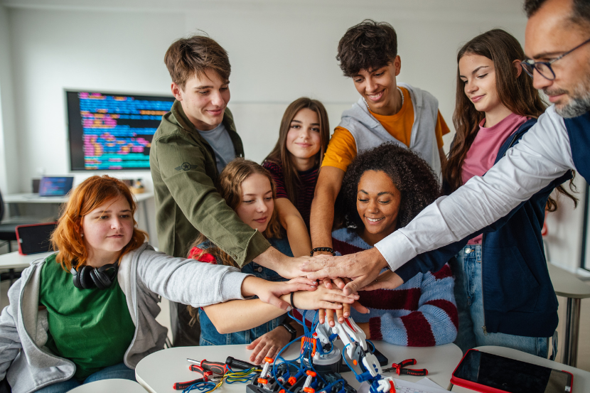 alunos de ensino médio técnico juntando as mãos em cima de projeto