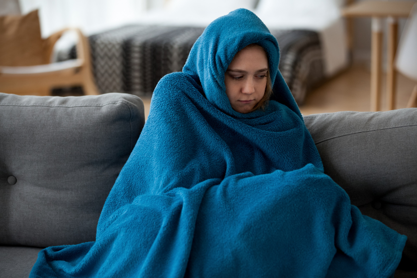 criança enrolada em cobertor azul no sofá com frio