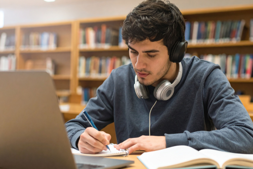Estudar com música é bom? garoto estudando com fones de ouvido no pescoço
