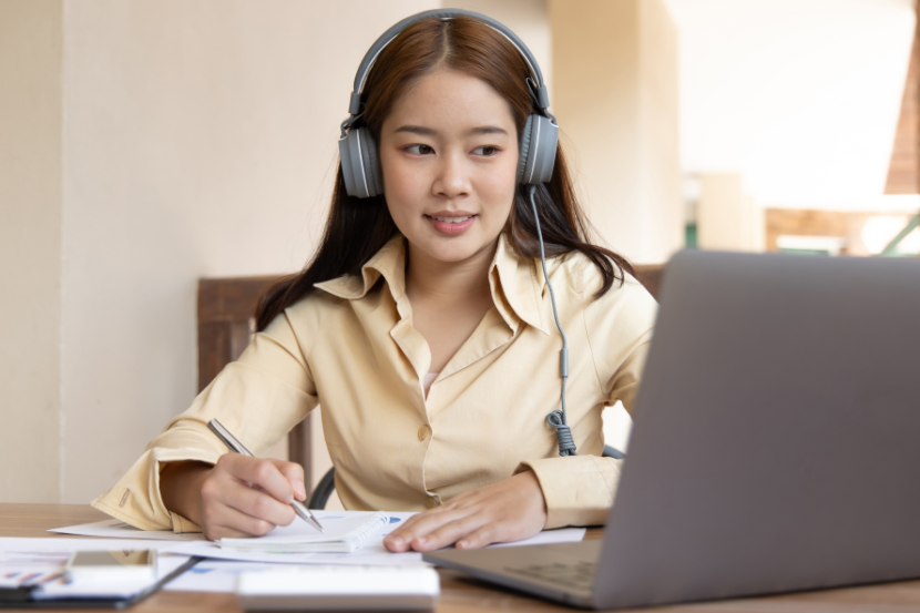 Estudar com música é bom? menina estudando com fones de ouvido, computador e outros materiais de estudo