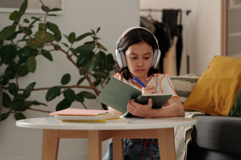 Estudar com música é bom? menina com fone de ouvido escrevendo no caderno
