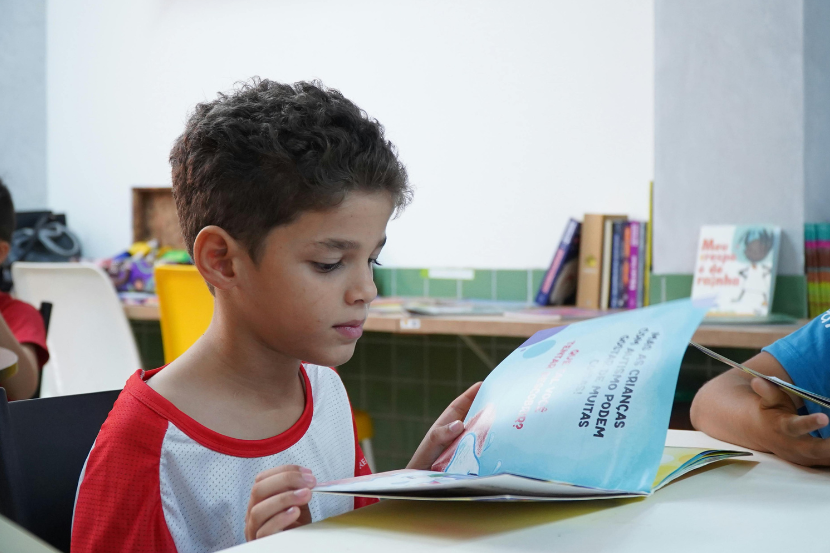 método fônico criança em idade de alfabetização lendo livro infantil em sala de aula